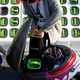 A person holds a battery over an electric scooter. There is a wall of green-handled batteries behind them.